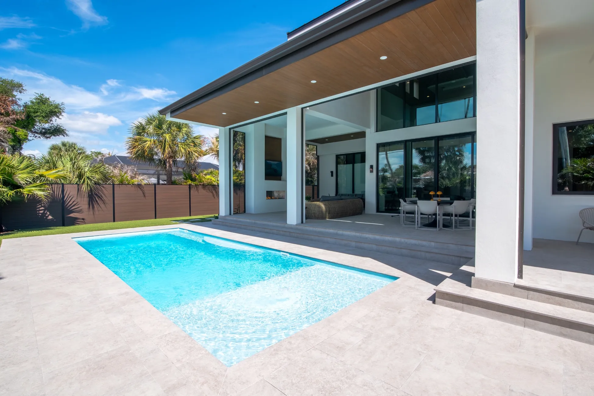 Covered patio outdoor living space with pool and fireplace in custom home in Vero Beach FL